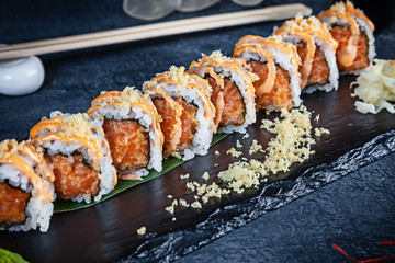 Close up view on set of sushi roll. Spicy roll with tuna and caviar served on black stone on dark background. Japanese cuisine. Copy space. Served sushi for menu. Healthy food, seafood
