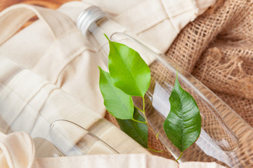 Bottle with clean water and the green leafs background close up
