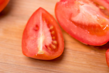 Juicy red tomato chopped on a wooden board on a white background
