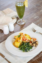 Spanish potato tortilla served with mushrooms, spinach and green detox drink on the wooden table, casual dining restaurant food	