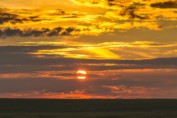 Fototapeta na wymiar Scenic sky during the sunset over a dark strip of field_