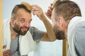 Man using comb in bathroom