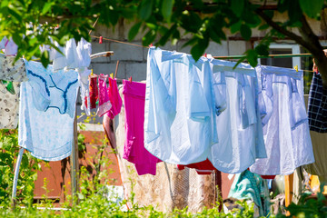 The washed shirts and linen dry on the street in the sunny weather_
