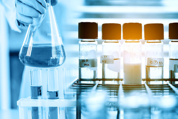 hand of scientist holding flask with lab glassware in chemical laboratory background, science laboratory research and development concept