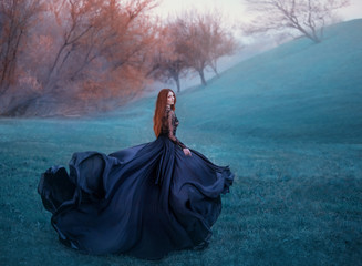 charming lady with red hair on green hill, scraping widow in long black flying dress and lace...