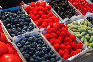 Delicious juicy colorful berries for sale at the market. Raspberry, mulberry, red currant, blueberry and others