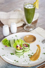 Thinly sliced raw zucchini rolls with a fresh green organic smoothie served on the restaurant table, vegetarian healthy snack