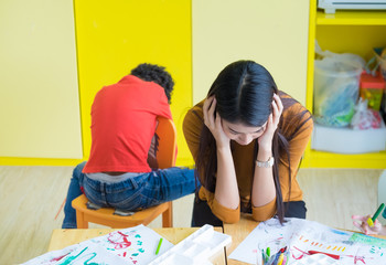 Teacher get headache with two naughty kids in classroom at kindergarten school