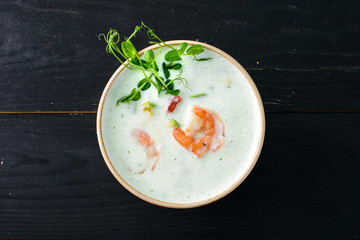 Vegetable cream soup with shrimps and croutons in bowl over wooden background with copy space