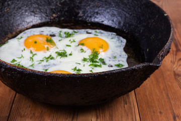 Old frying pan with fried eggs, closeup in selective focus