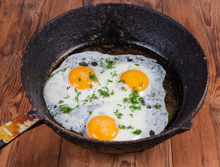 Fried eggs with unbroken yolks in the old frying pan