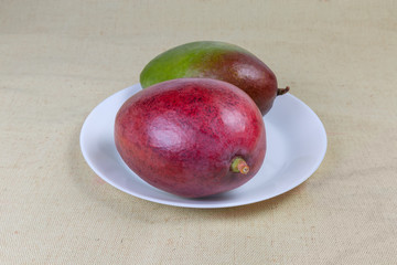 Two ripe mango fruits on the white dish