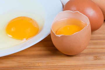Broken eggs in open shell and on dish close-up