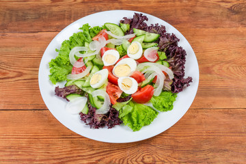 Vegetable salad with boiled quail eggs on the white dish
