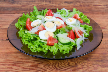 Vegetable salad with boiled quail eggs on the glass dish