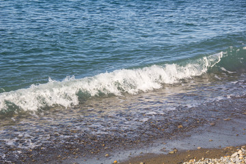 Fototapeta premium The sea foamy waves on an empty pebble beach