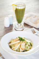 Battered salmon fish fillet dinner with noodles on a plate with a fresh green organic smoothie served on the restaurant table