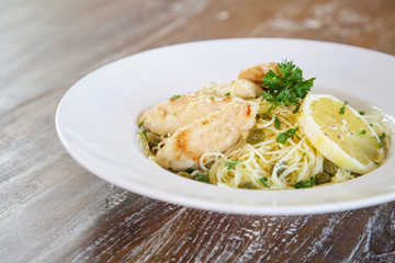 Battered salmon fish fillet dinner with noodles on a plate	