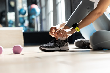 Woman's hands tying shoes Get ready to exercise at gym In a room with a window with natural light....