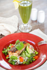 Grilled fish with green vegetable mix served with a glass of green detox smoothie, casual healthy dining concept