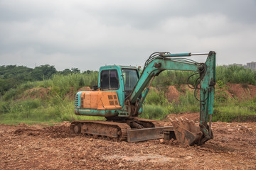 A blue mini excavator parked on the dirt in the field construction site