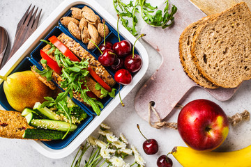 Cooking healthy food to lunch box. Sandwich, fruit, snacks on a gray background, top view.