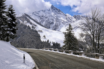 Fototapeta na wymiar Asphalt road Rossfeldstrasse in the Alps with snow on sides