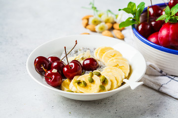 Chia pudding with banana, cherry and nuts in white plate.