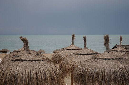 Sombrillas de brezo en la arena de la playa junto al mar.