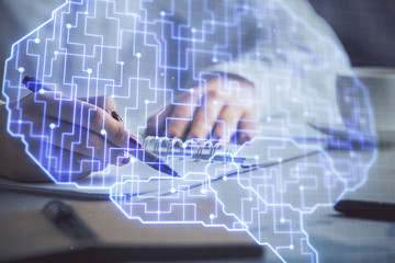 Multi exposure of woman's writing hand on background with brain hologram. Concept of brainstorming.