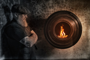 Obraz na płótnie Canvas Portrait of bearded hipster with tattooe on his arms with fireplace