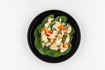Scrambled eggs with cherry tomatoes, bell pepper, cheese and spinach leaves as a part of nutritious breakfast menu isolated on white background