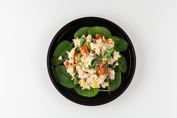 Scrambled eggs with cherry tomatoes, bell pepper, cheese and spinach leaves as a part of nutritious breakfast menu isolated on white background