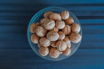Walnuts in the glass plate on the blue background
