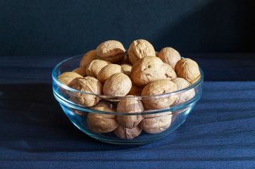 Walnuts in the glass plate on the blue background