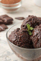 Chocolate ice cream with liquid chocolate and cinnamon sticks on a light concrete background.
