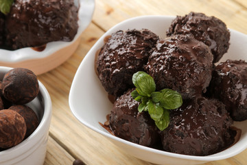 Chocolate ice cream with liquid chocolate and cinnamon sticks on a light concrete background.