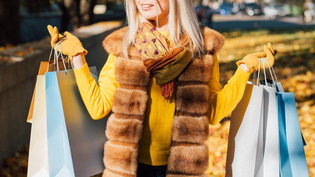 Fashionista Lifestyle. Cropped Shot Of Lady Standing With Shopping Bags, Smiling. Blur Fall City Street Background.