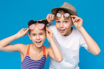 Cute boy and girl in summer wear looking over sugnlasses