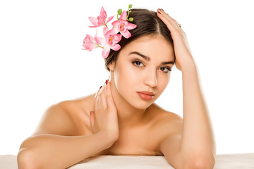 Young woman with makeup  posing with orchids on white background