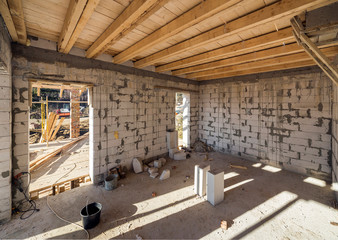 House room interior under construction and renovation. Energy saving walls of hollow foam insulation blocks, wooden ceiling beams and roof frame.