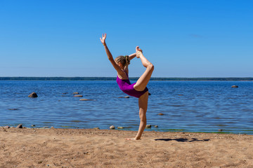 Fototapeta na wymiar Young girl doing light gymnastics on the beach on a sunny day.