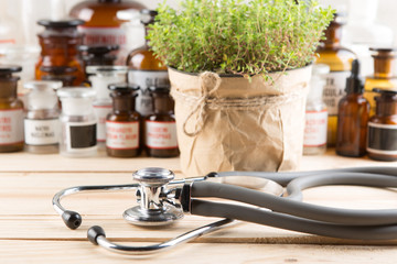 Alternative medicine concept medicine in bottles, medicinal herbs and stethoscope on a wooden table