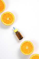 Citrus essential oil, vitamin c serum with fresh juicy orange fruit on white background. High dose vitamin c synthetic for skin. Flat lay, top view, copy space