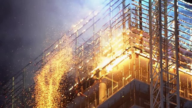 Particles and blazes of fire on the top of a skyscraper under construction in Warsaw during the night.