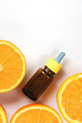 Bottle citrus essential oil and fresh juicy orange fruit on white background. High dose vitamin c synthetic for skin. Flat lay, top view, copy space