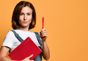 Pretty young beautiful woman standing, take notes, holding textbook notebook organizer in hand and pen