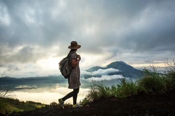 Woman enjoying sunrise from a top of mountain Batur, Bali, Indonesia.