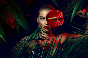 A beautiful tanned girl with natural make-up and wet hair stands in the jungle among exotic plants. - Powered by Adobe