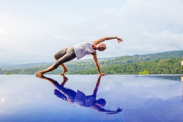 Caucasian woman practicing yoga by the pool